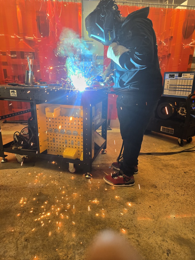 Hope High School agriculture students wearing welding helmets and protective gear practice MIG welding using new welding equipment in the Ag Department workspace.
