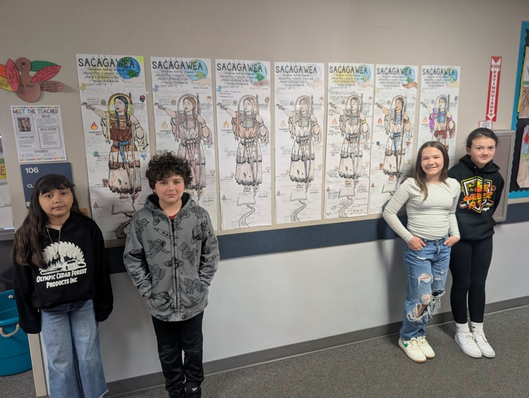 students standing near projects hanging on wall 