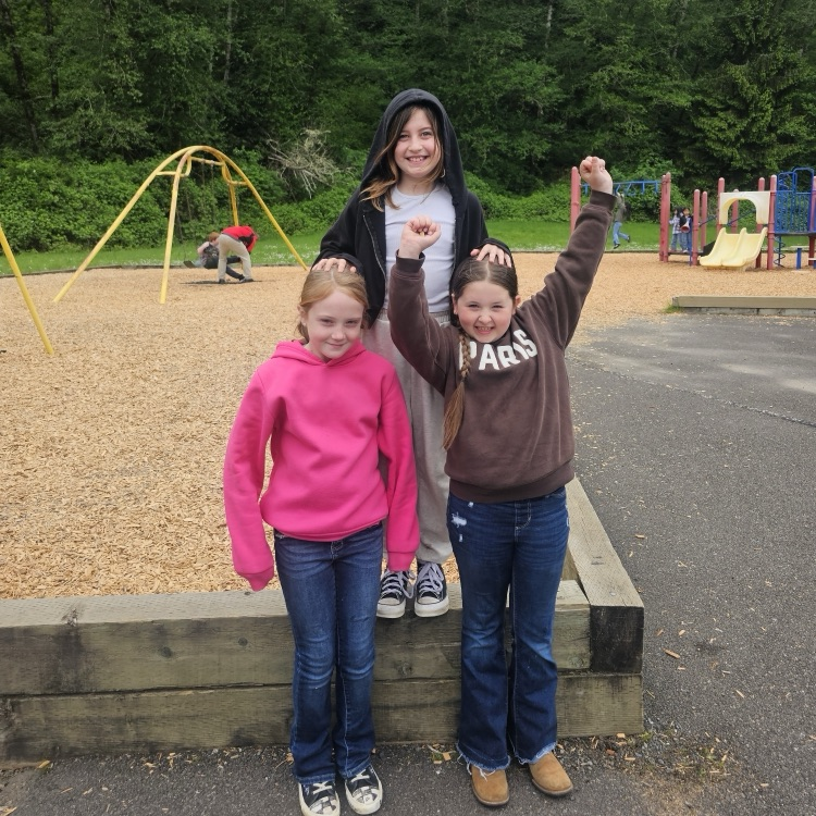 three students outside near playground 