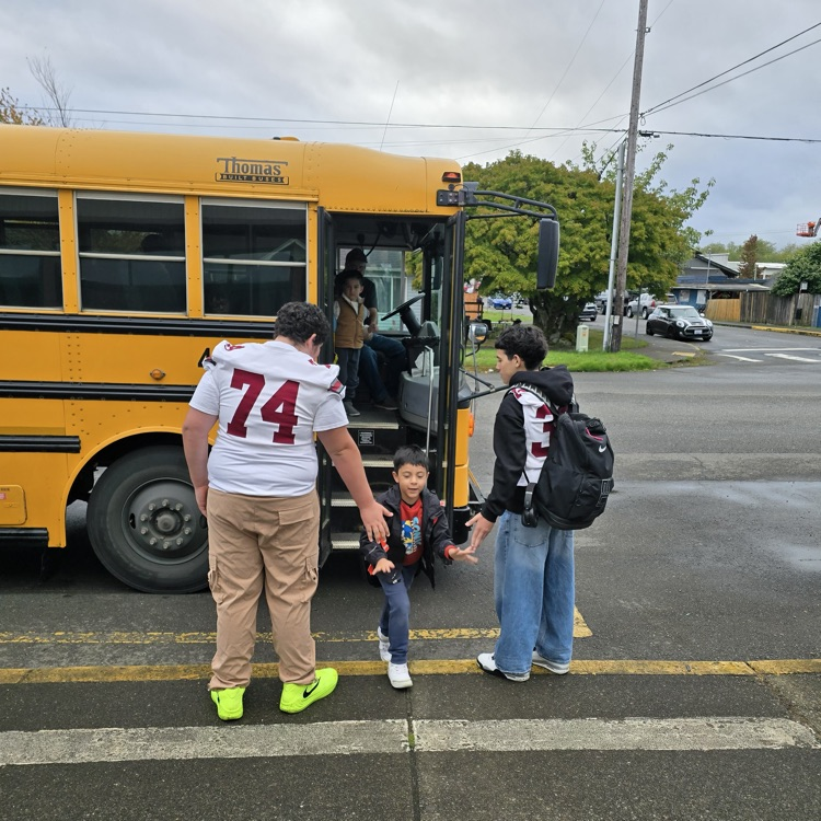football players at bus greeting students