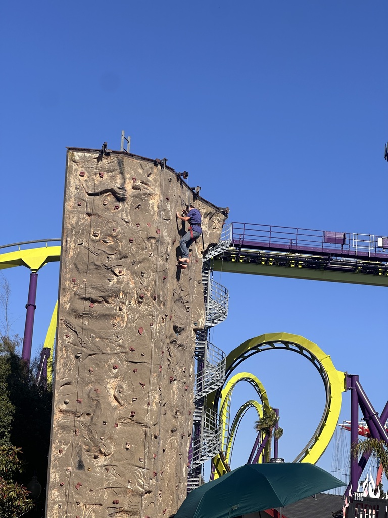 Students climbing to the top of a rock wall at Six Flags. 