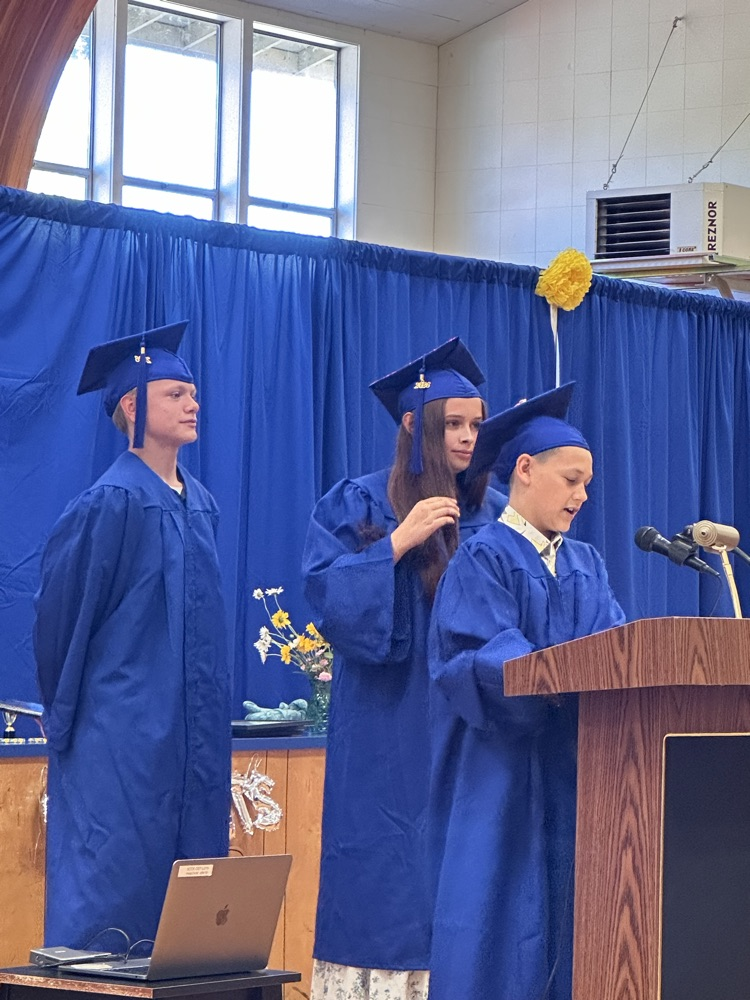 three students at the podium speaking 