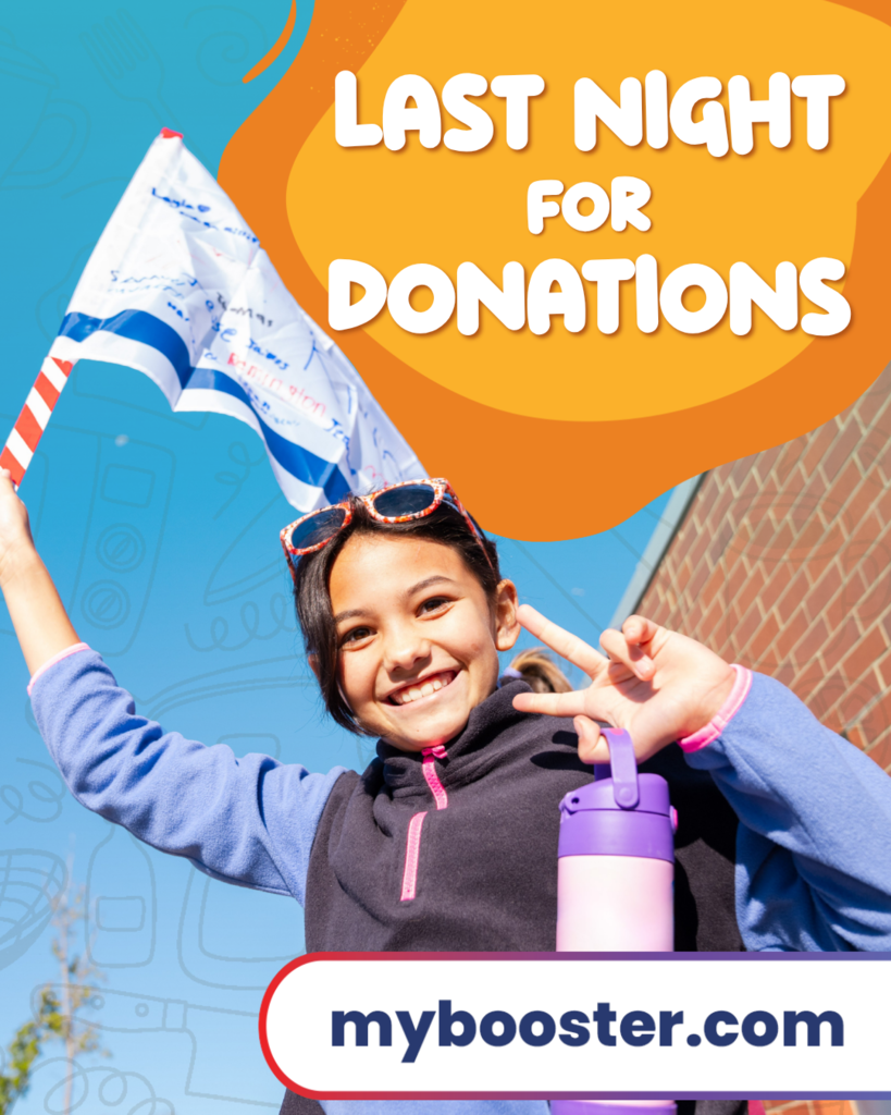 Young girl holding a flag and a purple water bottle, smiling, stands in front of a brick building.