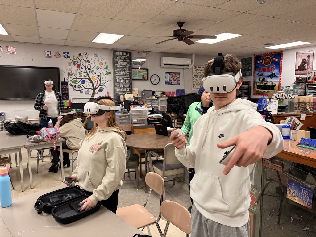 Students wearing virtual reality headsets and participating in simulated culinary or workplace environments in a classroom setting.