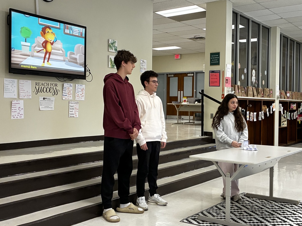 Students performing a nursery rhyme in Spanish while interacting with sensory stations created by classmates.