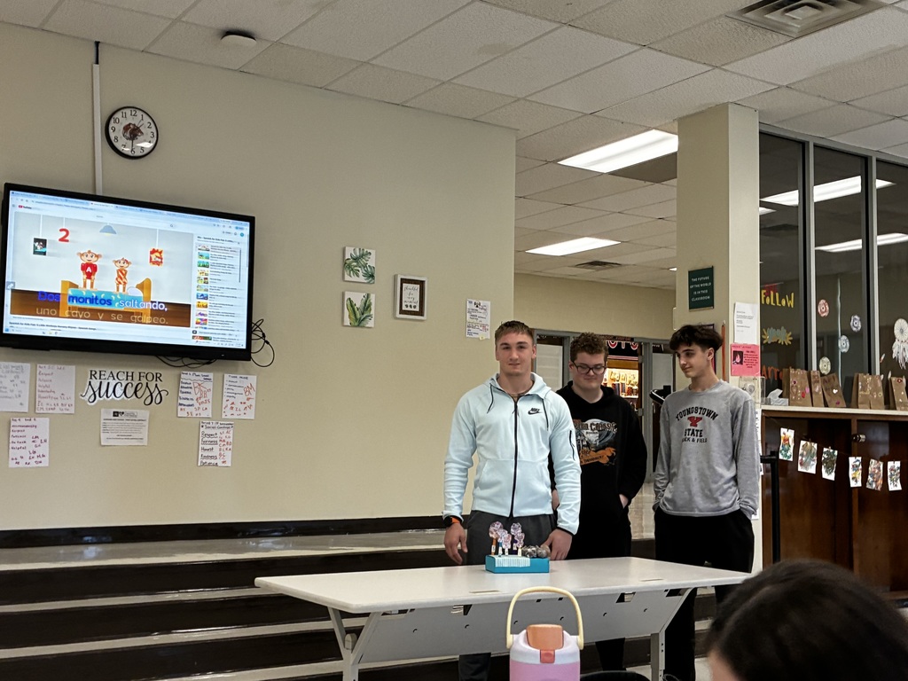 Students performing a nursery rhyme in Spanish while interacting with sensory stations created by classmates.