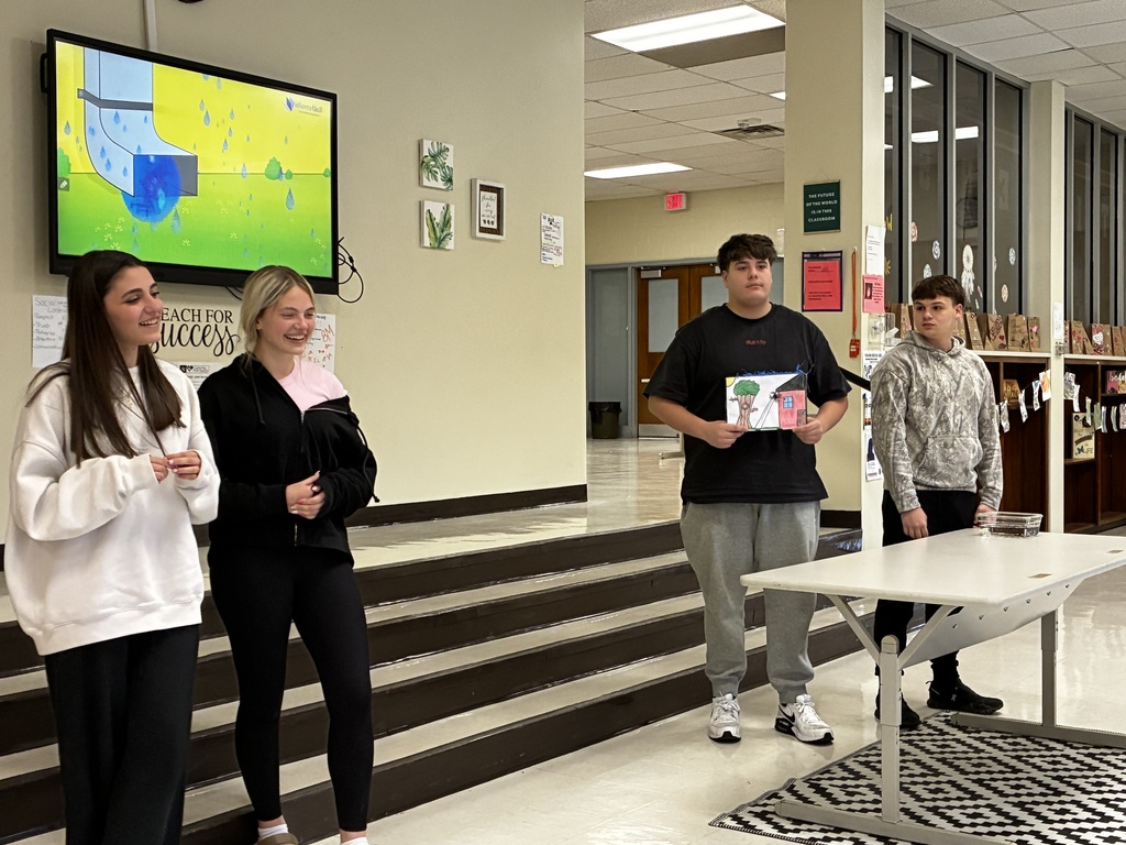 Students performing a nursery rhyme in Spanish while interacting with sensory stations created by classmates.