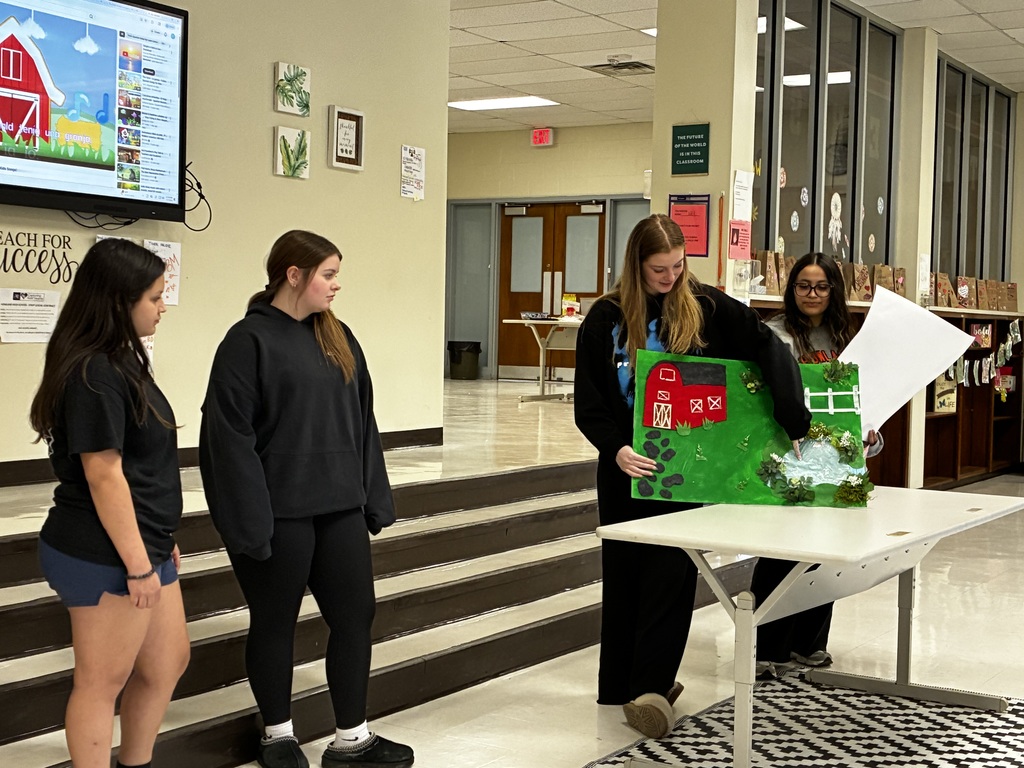 Students performing a nursery rhyme in Spanish while interacting with sensory stations created by classmates.
