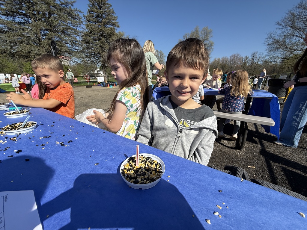 Students celebrating Earth Day outside, touring the Tiger Den, making bird seed, drawing with chalk, painting rocks, and playing with parachutes.