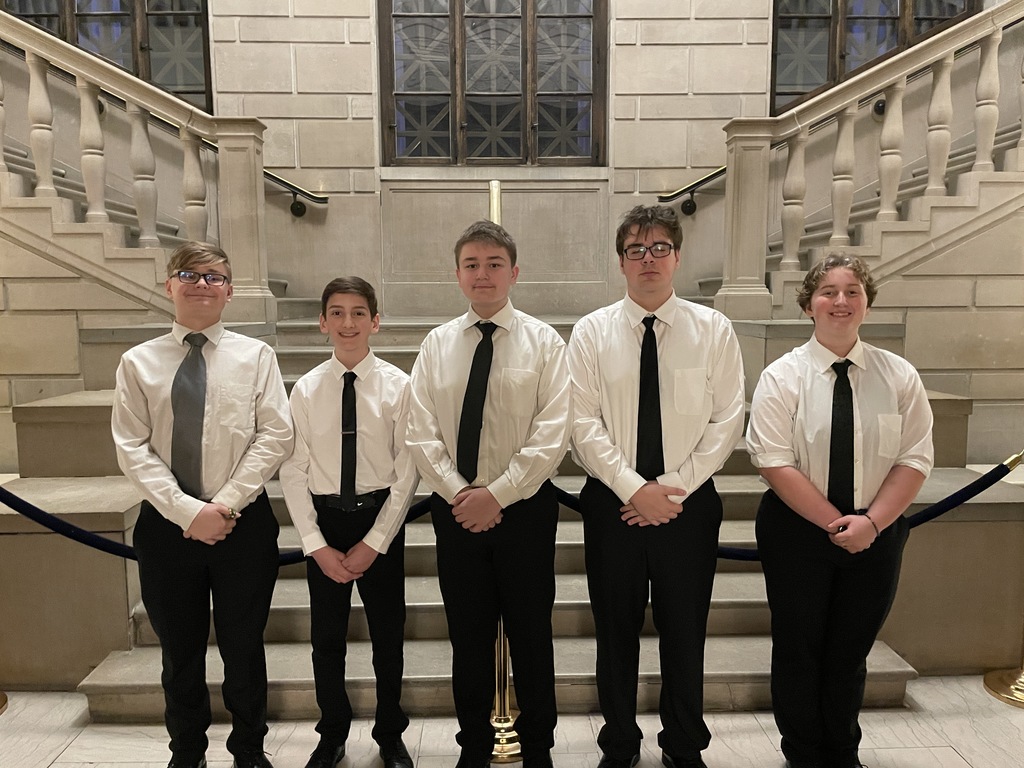 Five Howland band students stand together holding their instruments after performing in the Stambaugh Youth Concert Band spring concert.