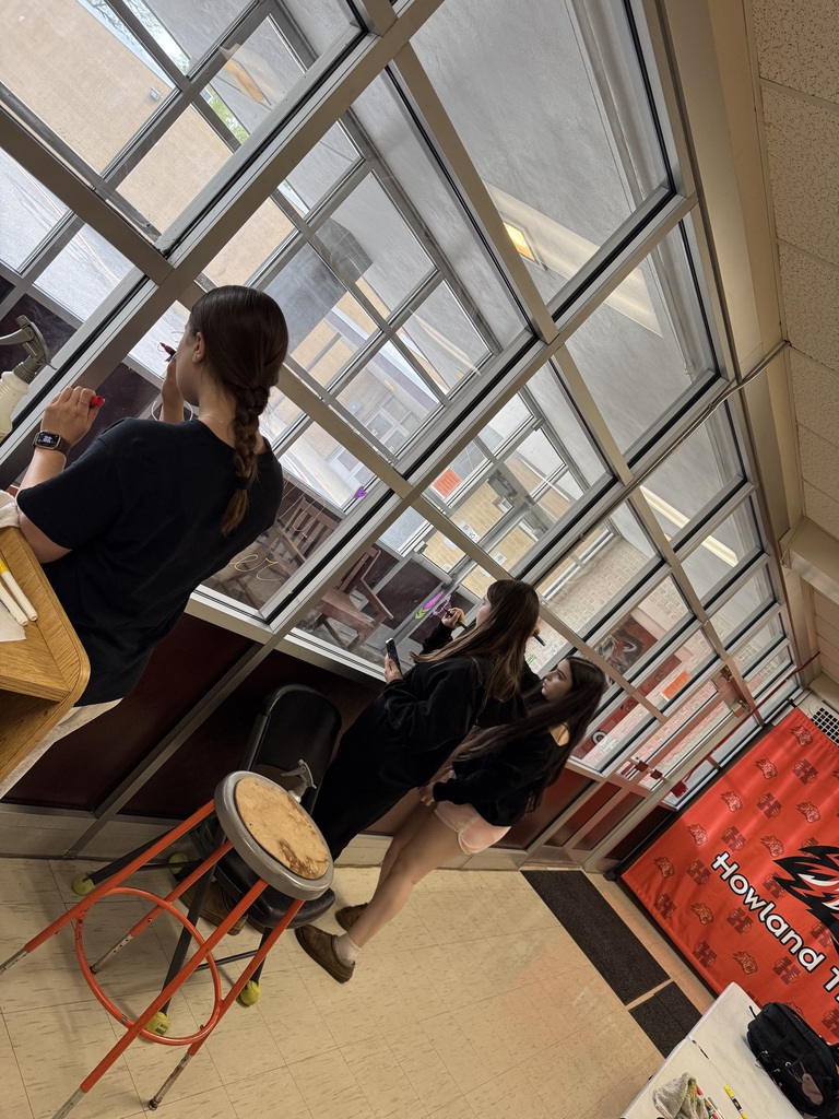 Students from the Health, Safety, and Wellness Club decorate school windows with colorful artwork and positive messages before summer break.