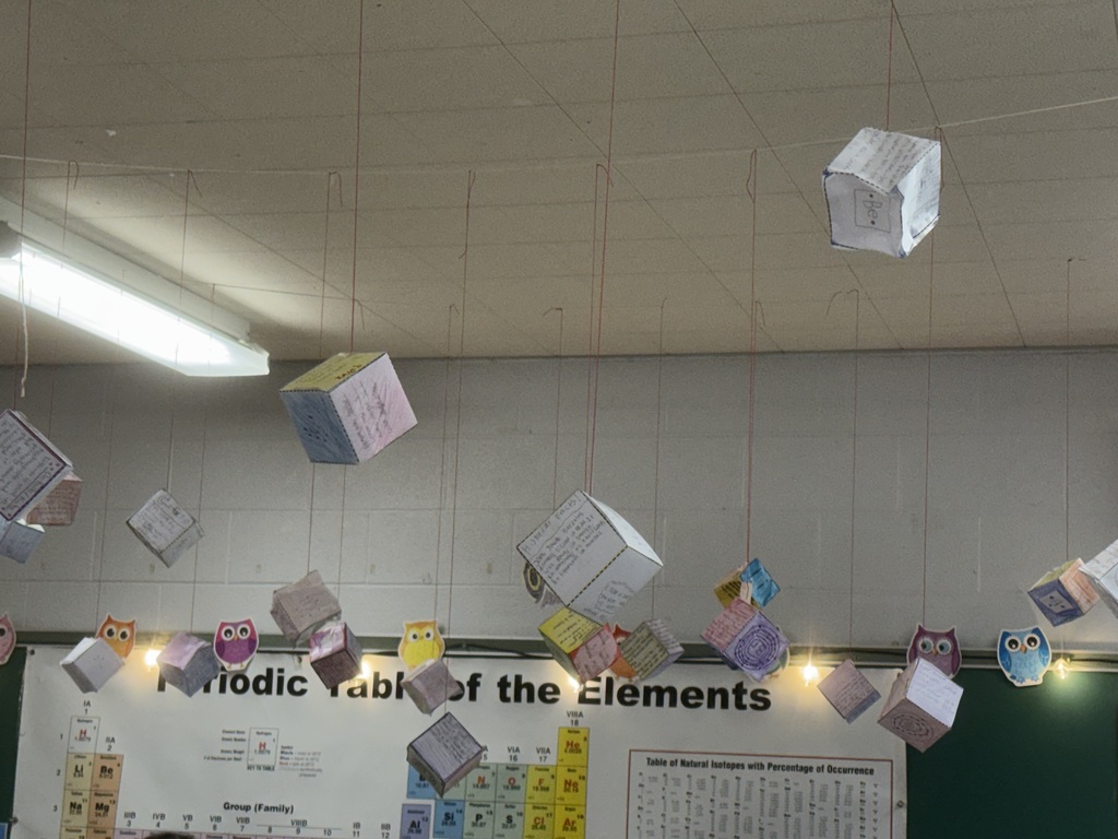 Howland Junior High School seventh-grade students display element cubes, while eighth-grade students investigate friction by testing toy cars on different surfaces and graphing their results.