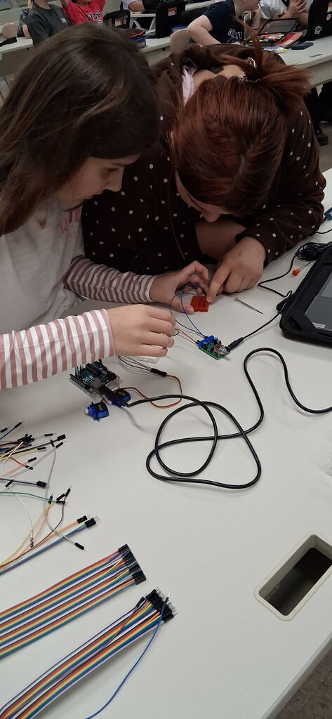 Howland Intermediate School students participate in Ohio Code Scholar, with Kenley and Ryeliegh working on Arduino wiring and audio while classmates develop ideas for 3D designs.