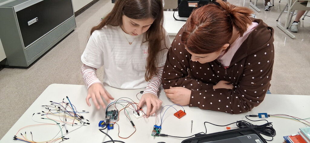 Howland Intermediate School students participate in Ohio Code Scholar, with Kenley and Ryeliegh working on Arduino wiring and audio while classmates develop ideas for 3D designs.