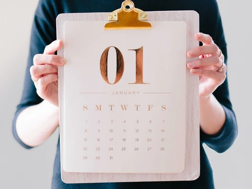 Person holding a clipboard displaying a  calendar