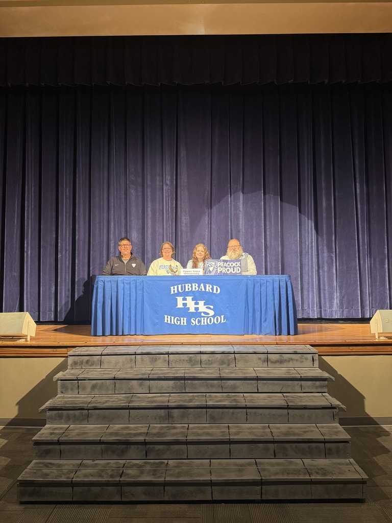 Macy Kegley: Student-athlete signing a letter of intent for wrestling at Upper Iowa, seated at a table with supporters gathered behind.