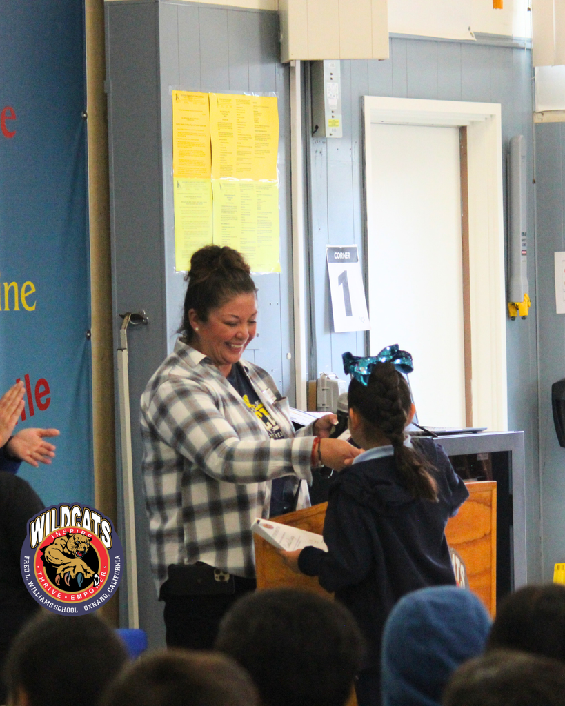 teacher smiles as kid receives award