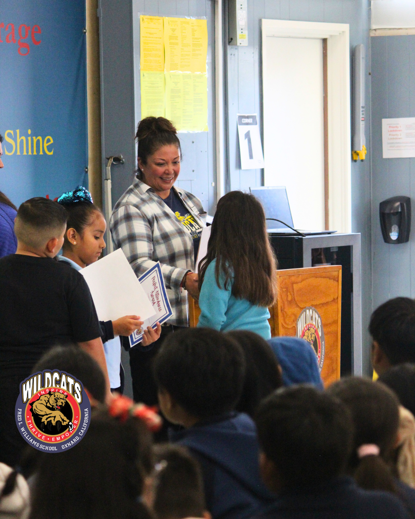 teacher smiles as kid receives award