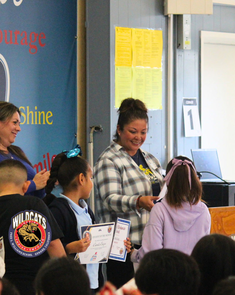 teacher smiles as kid receives award