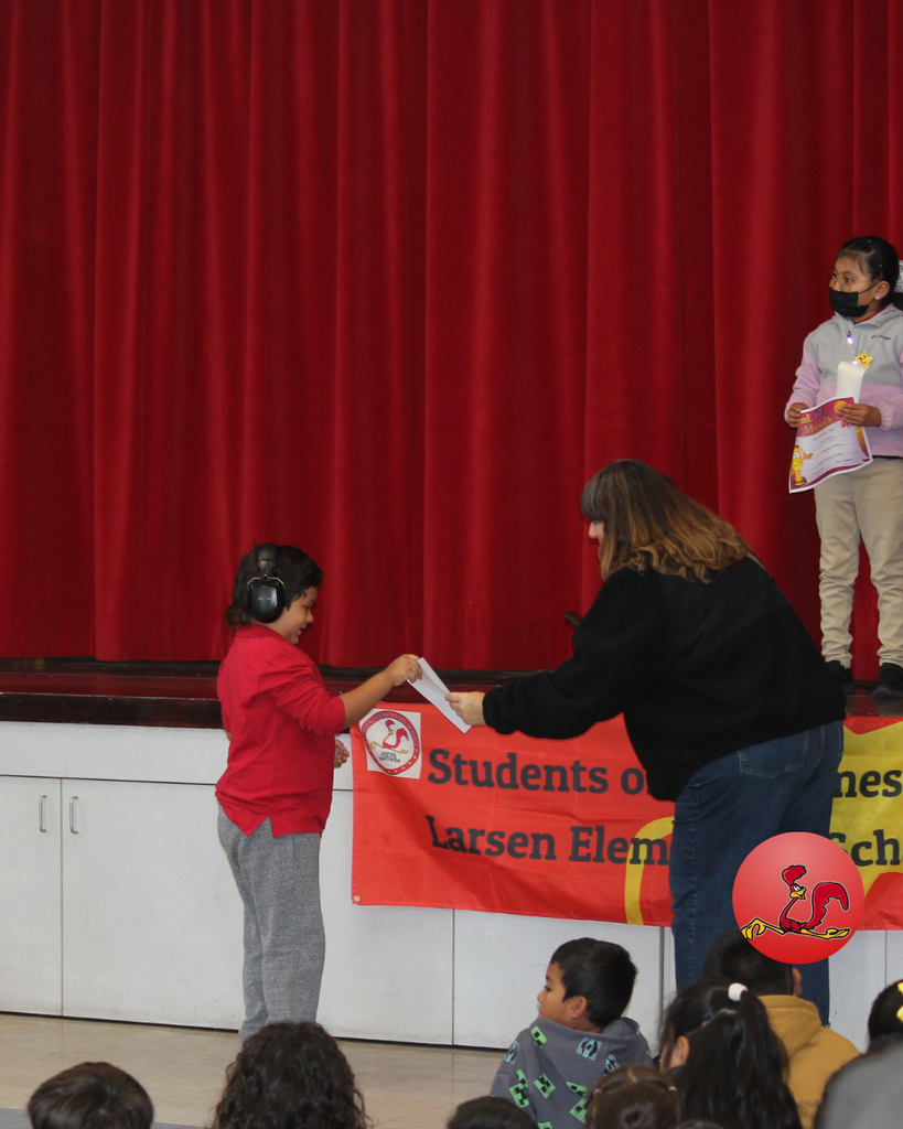 teacher smiles as kid receives award