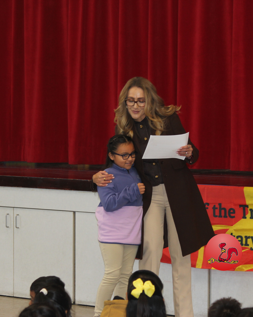 teacher smiles as kid receives award