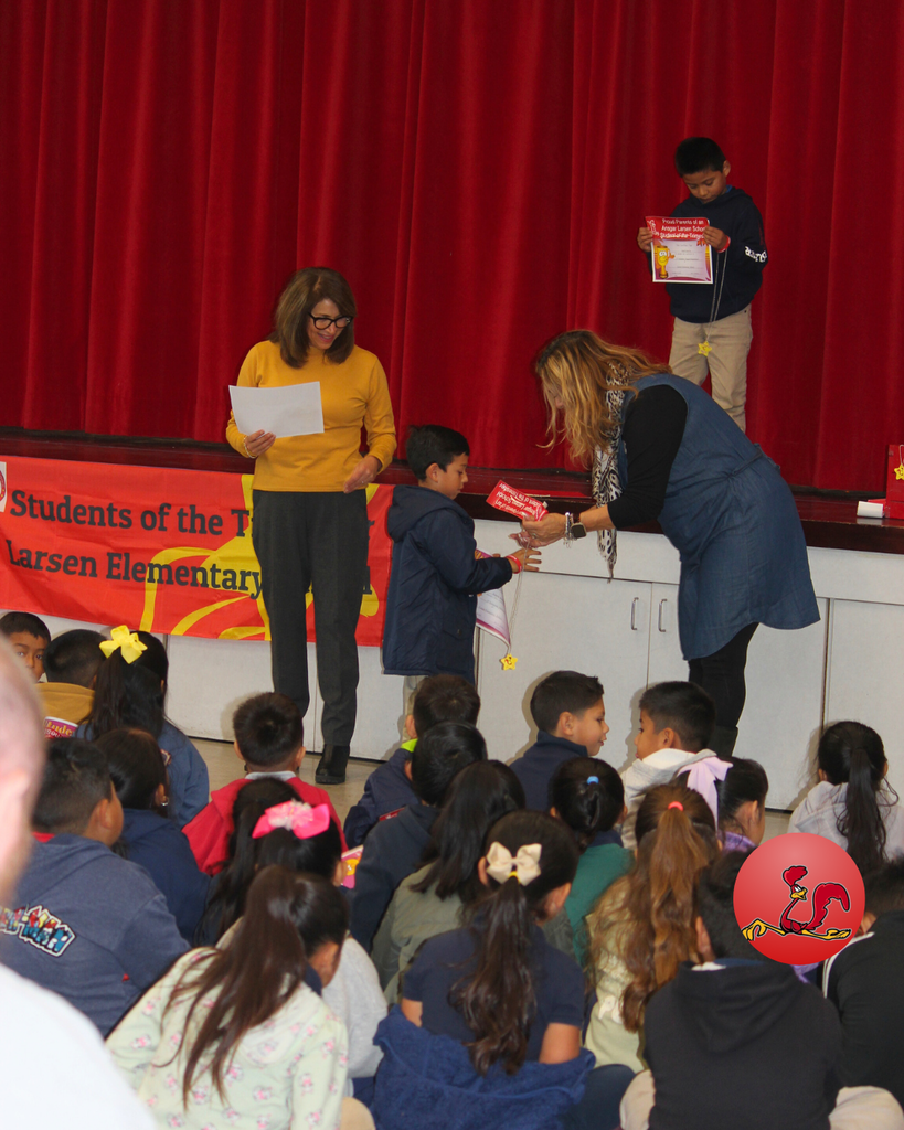 teacher smiles as kid receives award