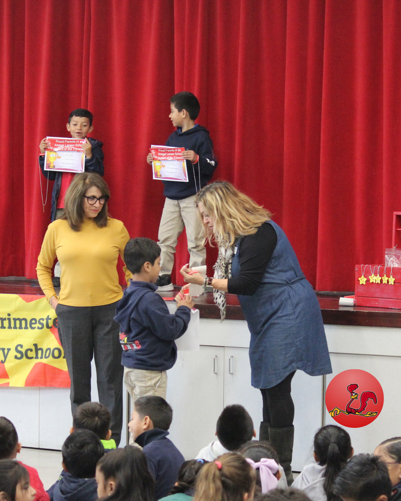 teacher smiles as kid receives award
