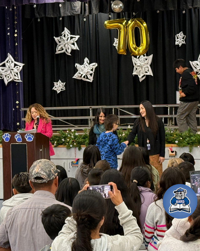 teacher smiles as kid receives award