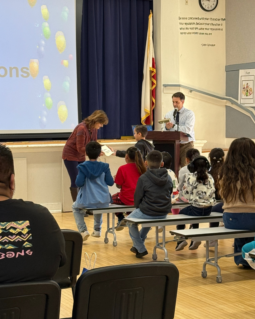 teacher smiles as kid receives award