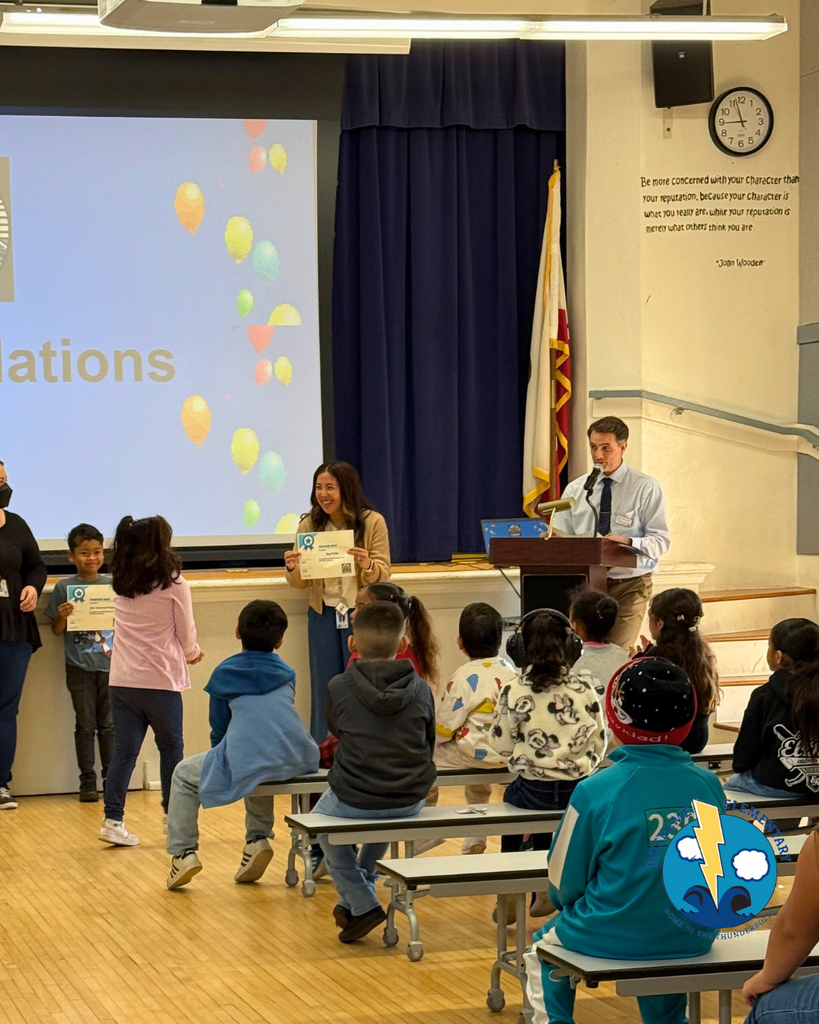 teacher smiles as kid receives award