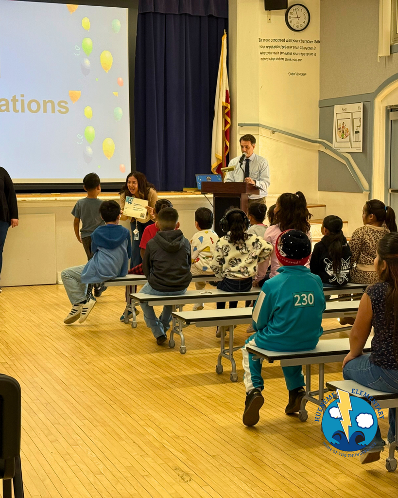 teacher smiles as kid receives award