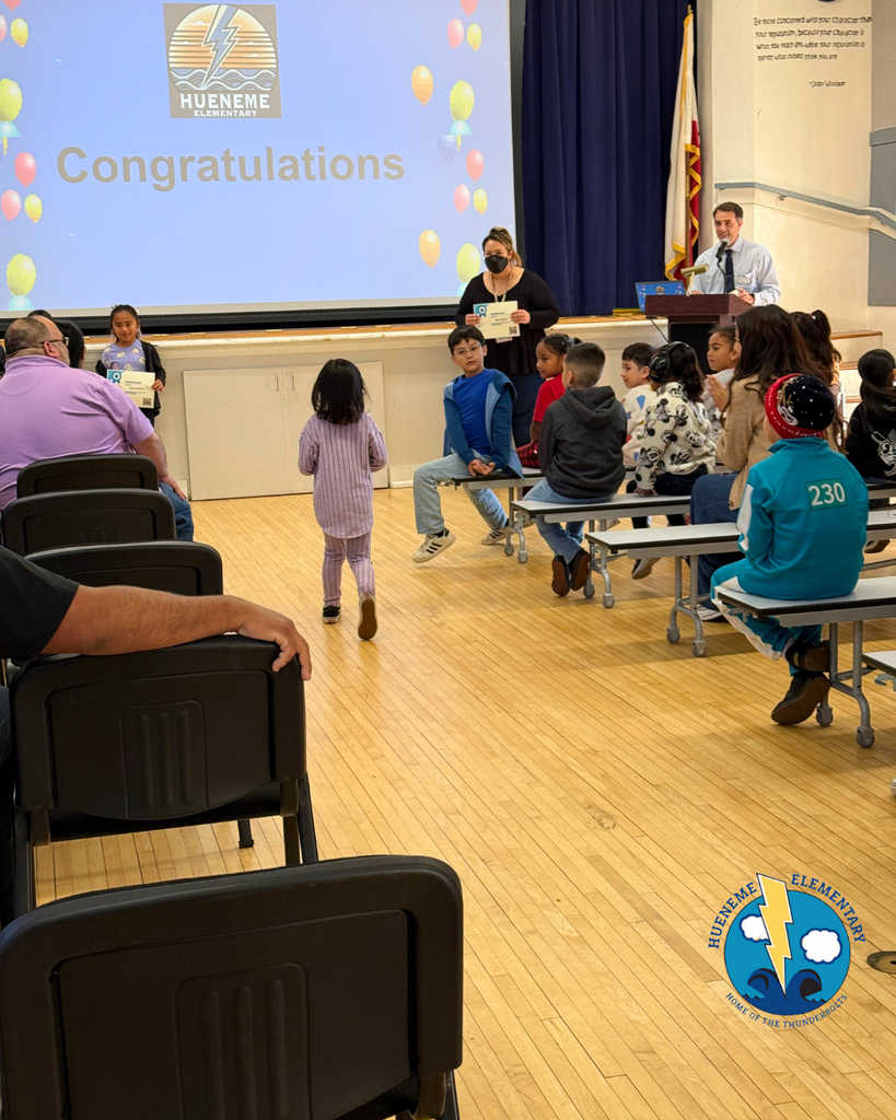 teacher smiles as kid receives award