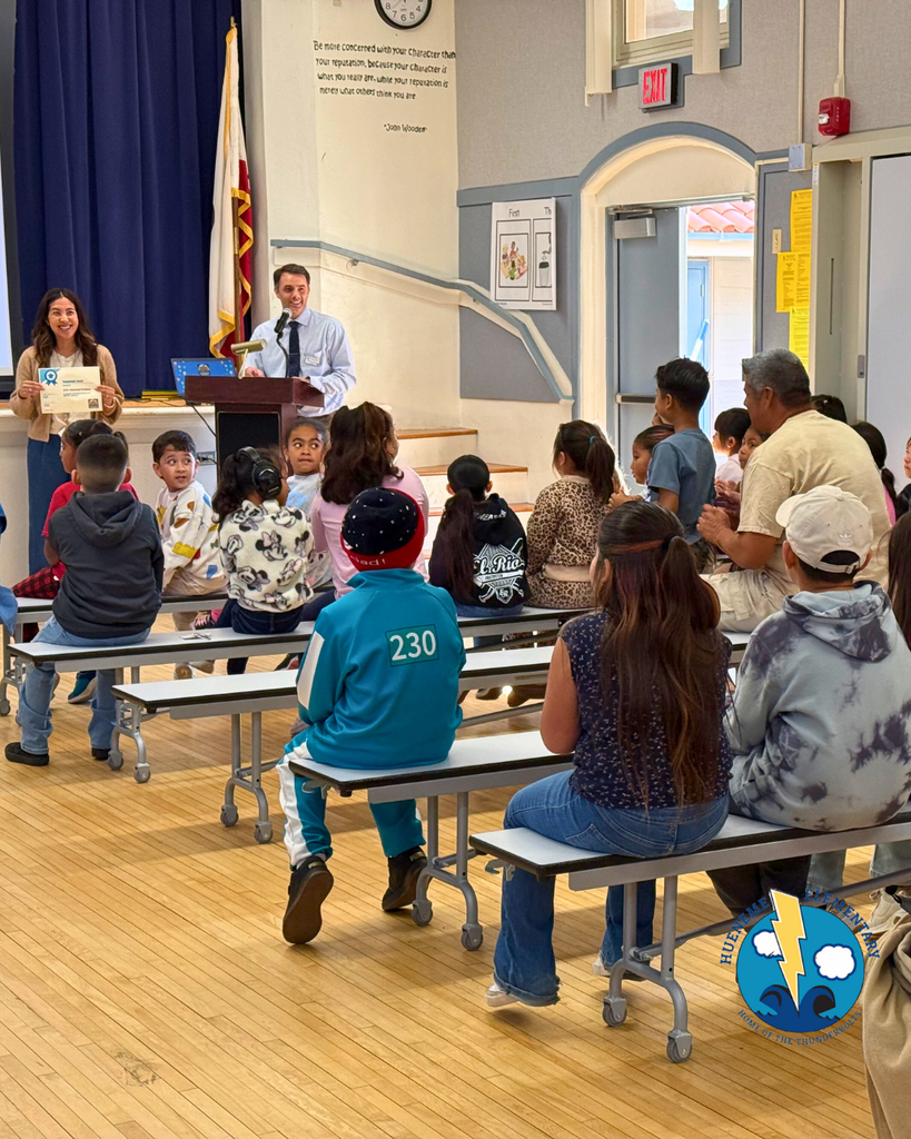 teacher smiles as kid receives award