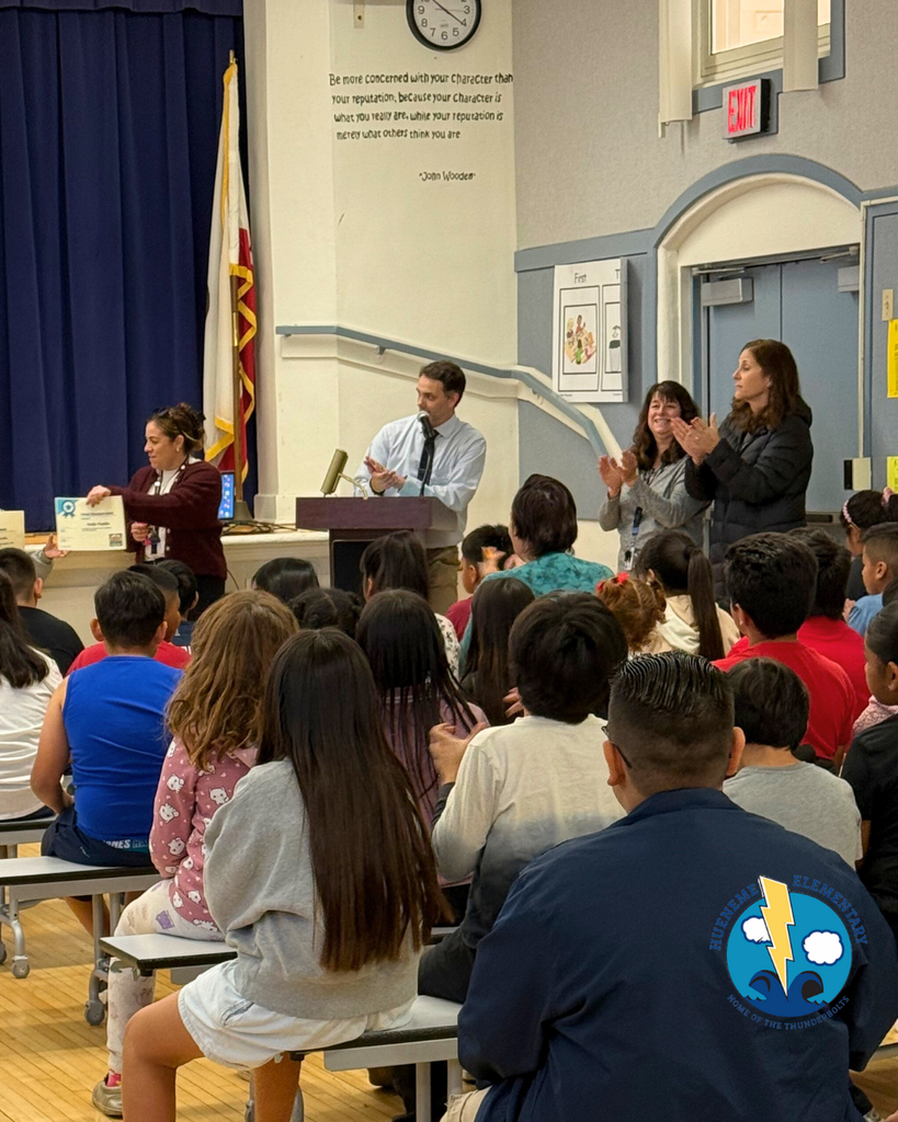 teacher smiles as kid receives award