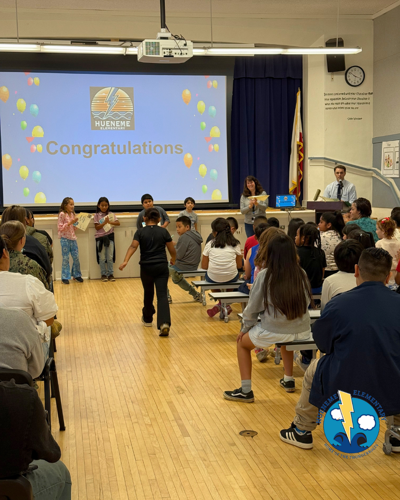 teacher smiles as kid receives award