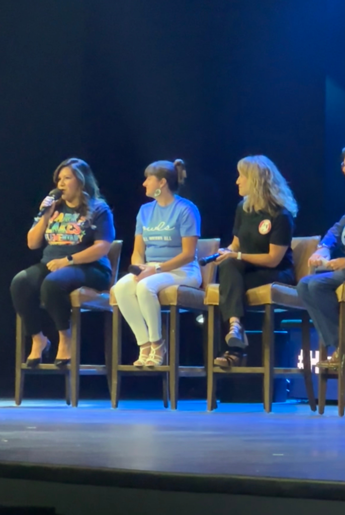 Principal Thomas speaks on stage with a panel or principals to the teachers at 25-26 convocation.