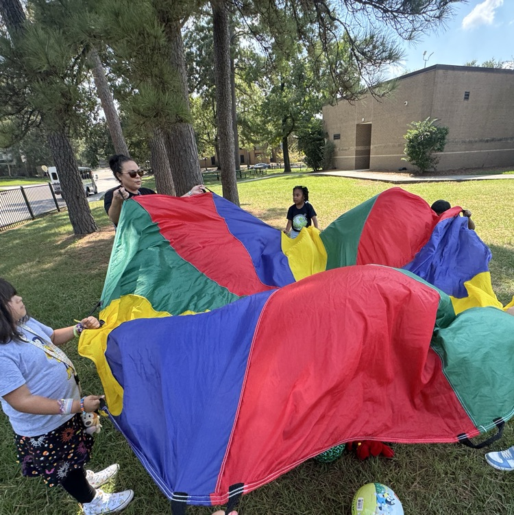 kids and teacher playing with parachute