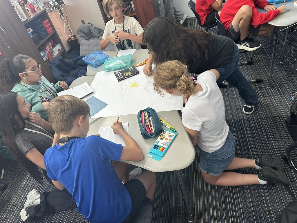 Students working at desk on book club posters