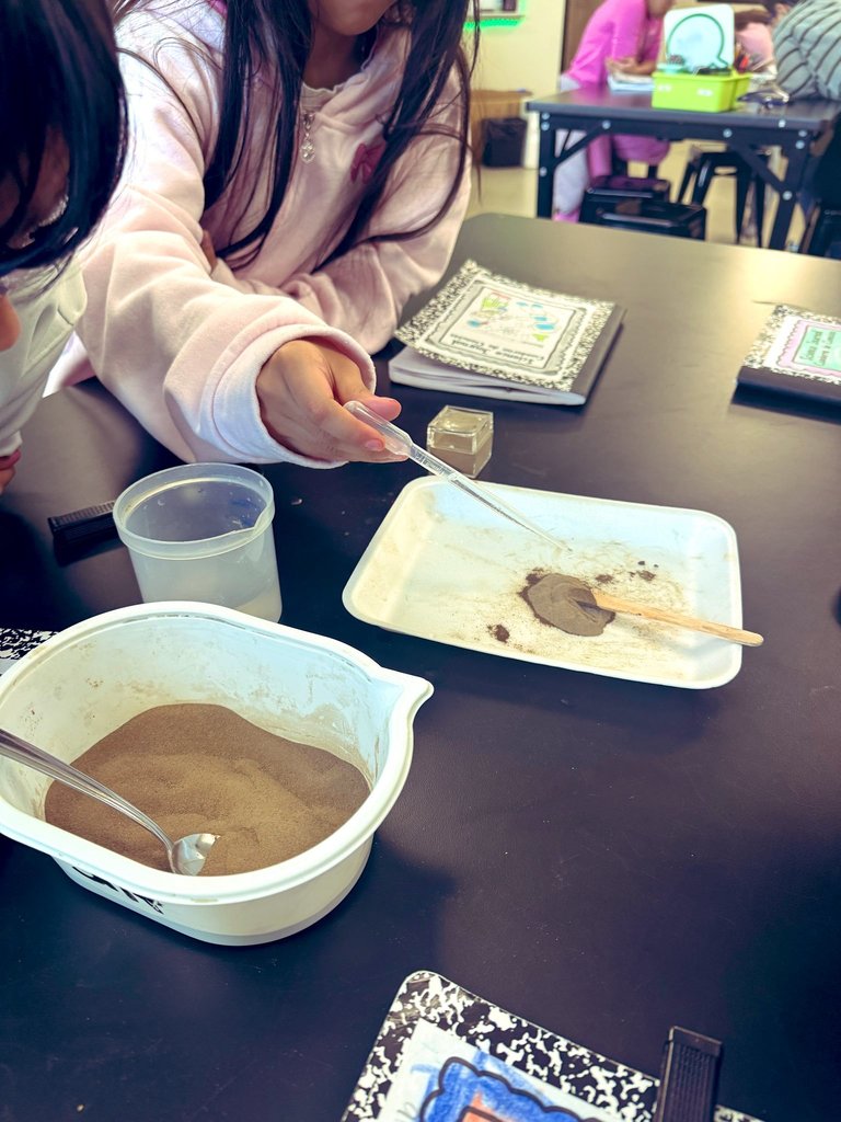 Students adding water to clay.