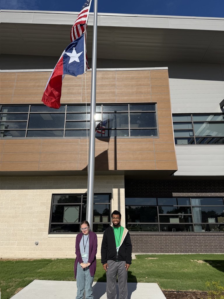 students raising flag on flagpole outside the new Mosaic building