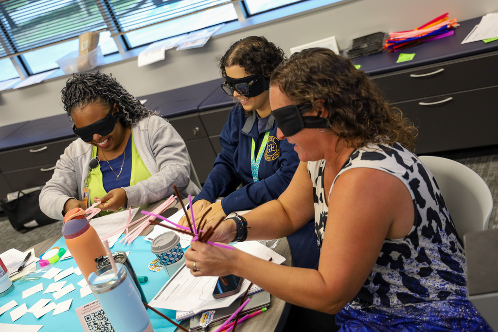 women using pipe cleaners to create a project while blind folded