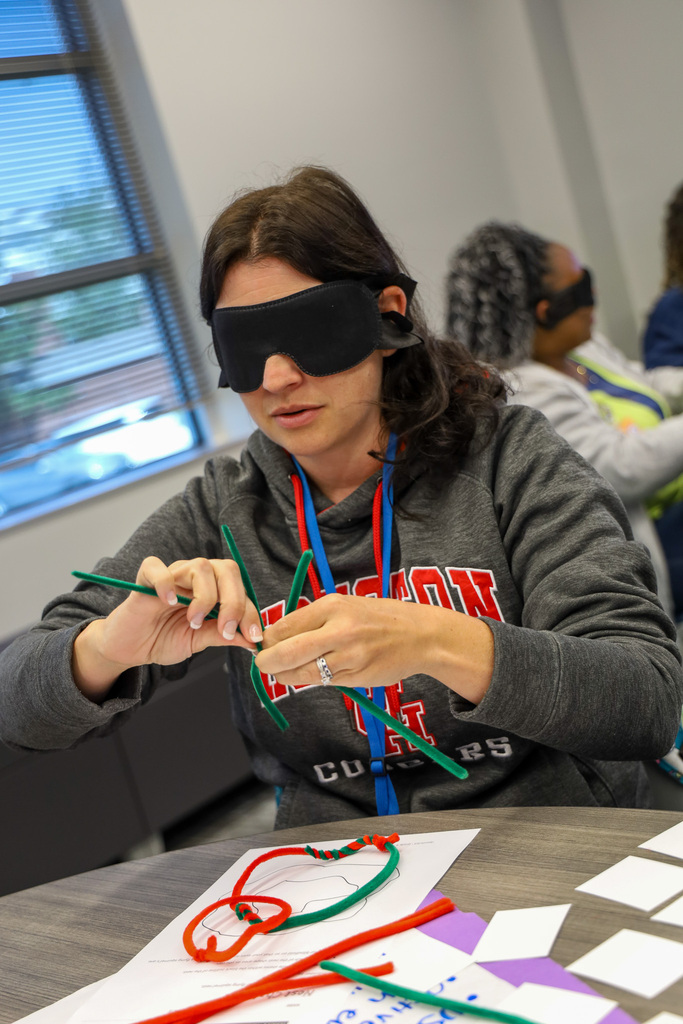 woman using pipe cleaners to create a project while blind folded
