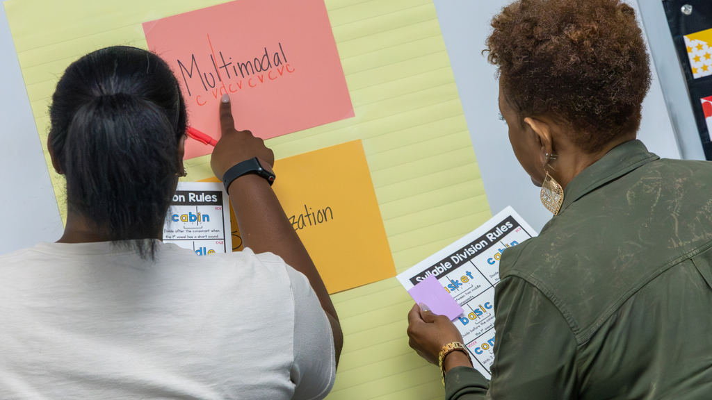 two educators discussing syllable division rules in front of chart paper