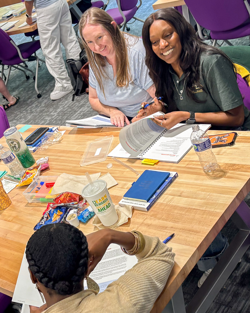 group of educators smiling with open books on the table