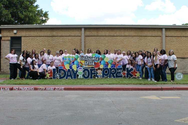 ECC staff takes a photo with the first day of school sign  
