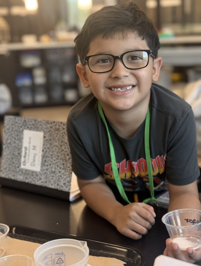 Student holding a cup of sugar. Adding it to a beaker filled with water and test if it will or will not dissolve in water.