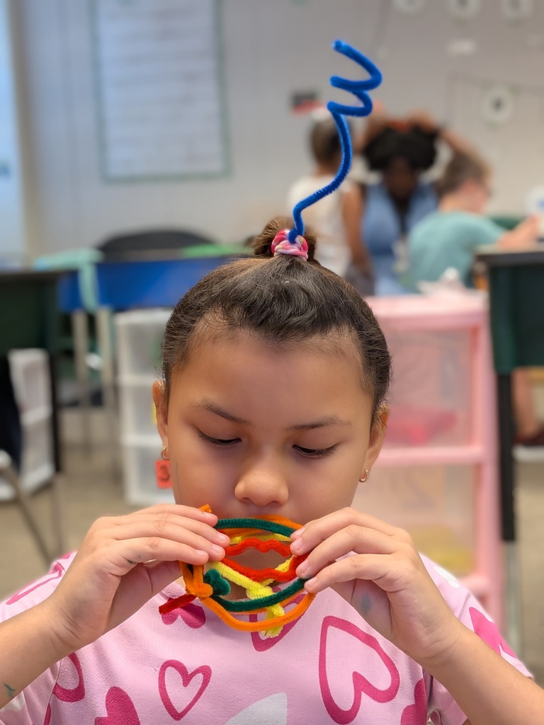 Studnet pretending to eat a sandwhich made from pipecleaners