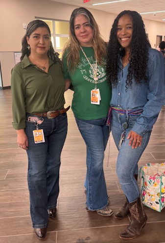 Three teachers standing together, wearing boots and belts for Boots and Ribbons Day.