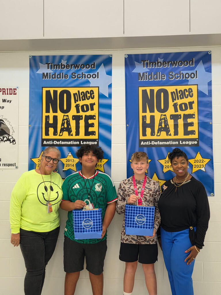 Twp adults and two children stand next to each other. Each child holds a blue bag.
