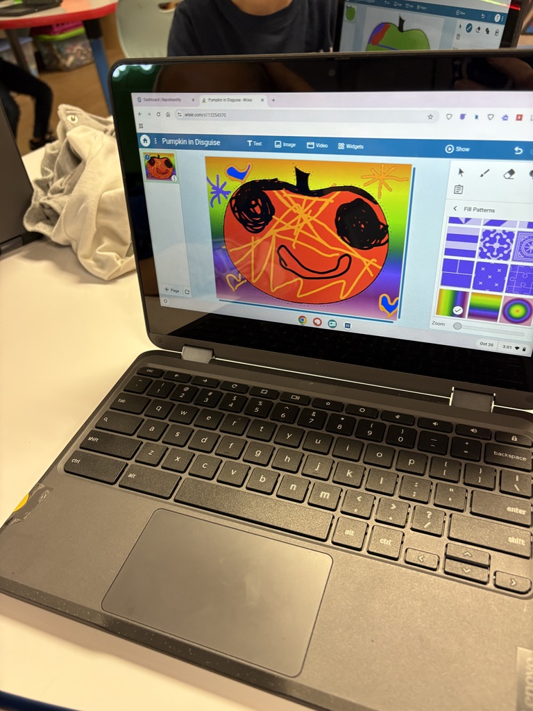 Laptop with a pumpkin drawing displayed on screen. The keyboard is open. A white table is behind the laptop.